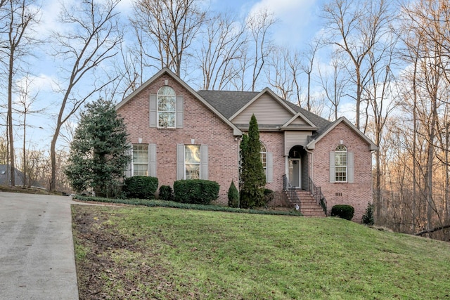 traditional home with a front yard, crawl space, brick siding, and a shingled roof