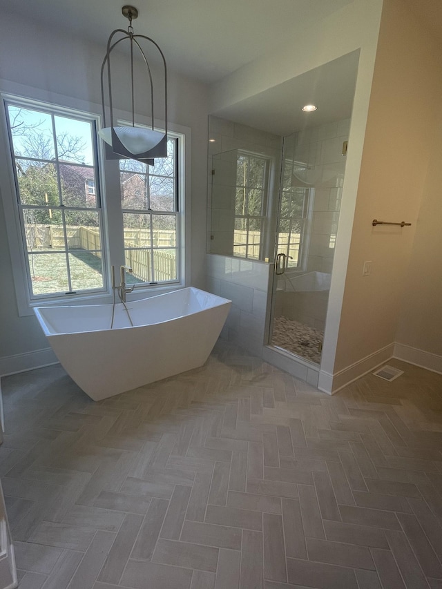 full bath featuring baseboards, a freestanding bath, and a shower stall