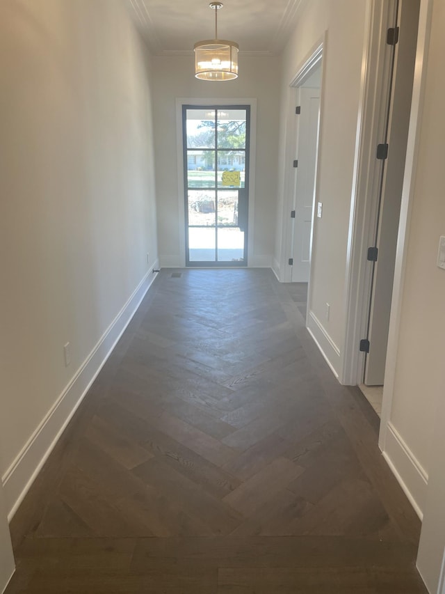 hall with dark wood-style floors, baseboards, and ornamental molding