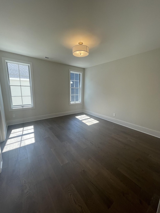 empty room featuring dark wood-type flooring and baseboards