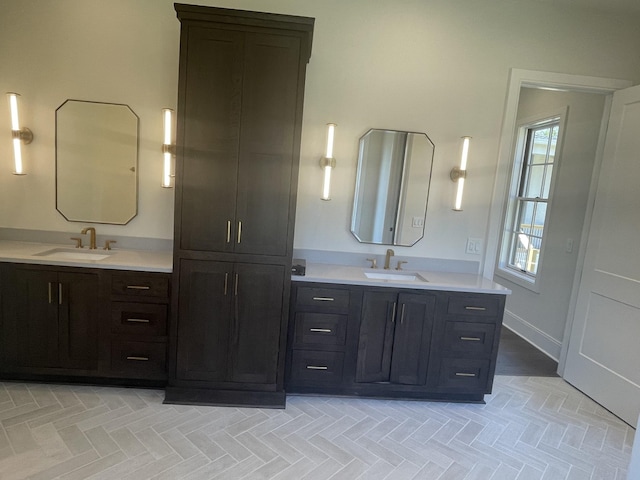 full bathroom with a sink, baseboards, and two vanities