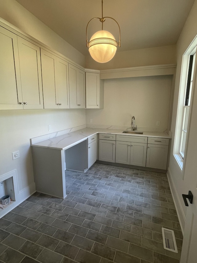 washroom featuring baseboards, cabinet space, visible vents, and a sink