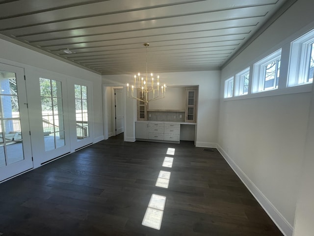 unfurnished dining area featuring baseboards, dark wood-style flooring, and a chandelier