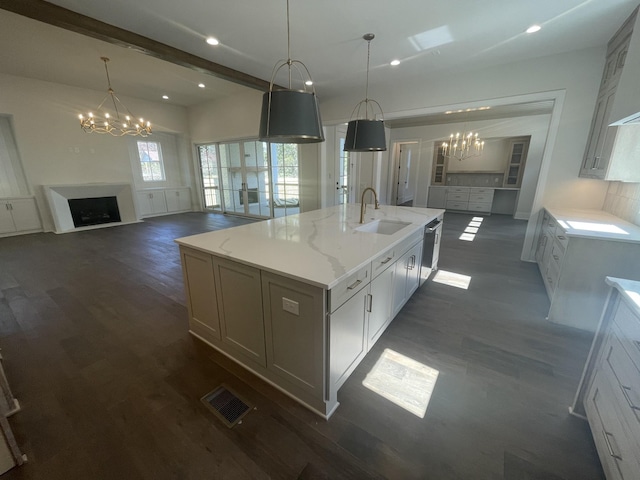 kitchen with a notable chandelier, a sink, open floor plan, a fireplace, and a large island with sink