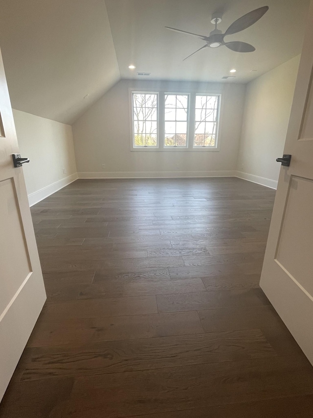 additional living space featuring visible vents, a ceiling fan, dark wood-style floors, baseboards, and lofted ceiling