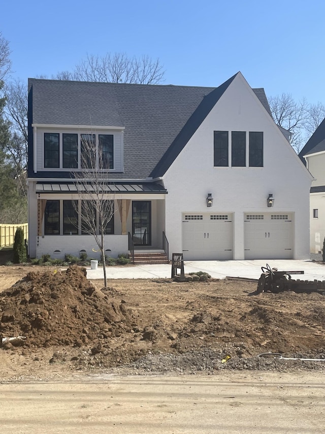 view of front facade with driveway, a garage, and roof with shingles