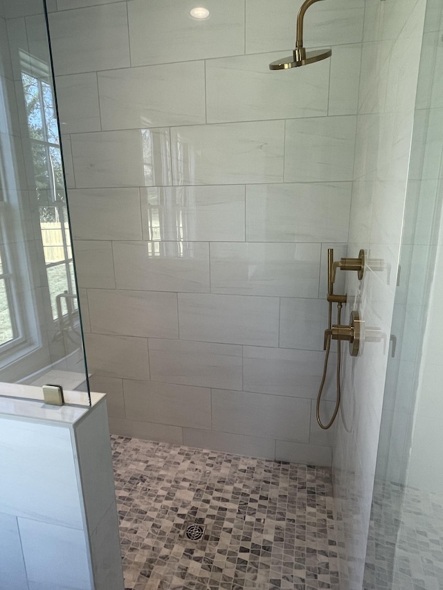 full bathroom with a tile shower and a wealth of natural light