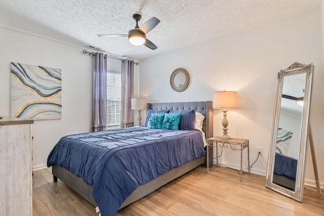 bedroom with baseboards, a textured ceiling, light wood-style flooring, and a ceiling fan