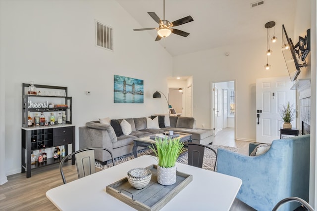 dining area featuring visible vents, ceiling fan, high vaulted ceiling, and light wood-style floors