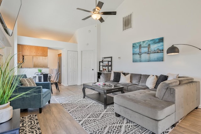 living room featuring light wood-type flooring, visible vents, high vaulted ceiling, and a ceiling fan