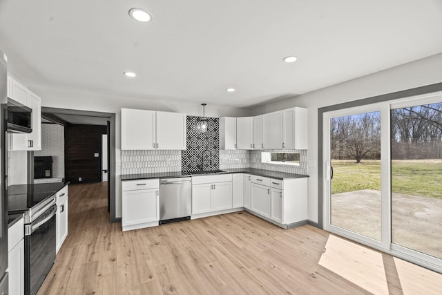 kitchen featuring tasteful backsplash, dark countertops, oven, dishwasher, and light wood-style flooring