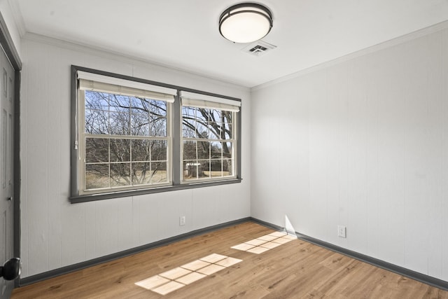 unfurnished room featuring crown molding, wood finished floors, visible vents, and baseboards