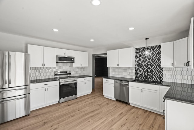 kitchen with decorative light fixtures, dark countertops, light wood-style floors, appliances with stainless steel finishes, and white cabinets