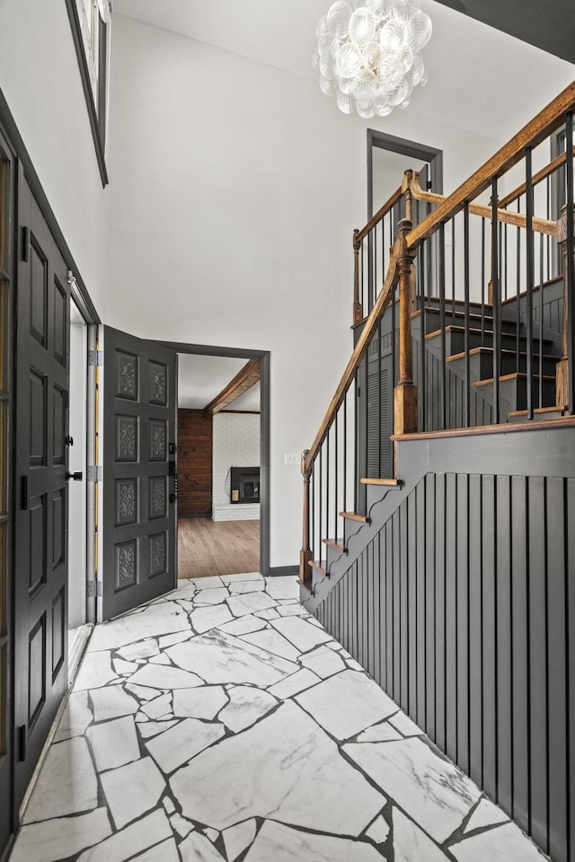 entryway featuring a high ceiling, an inviting chandelier, a fireplace, and stairs