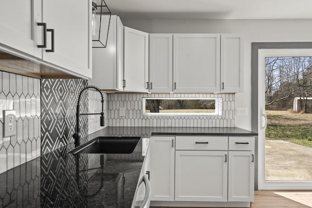 kitchen featuring backsplash, white cabinetry, a healthy amount of sunlight, and a sink