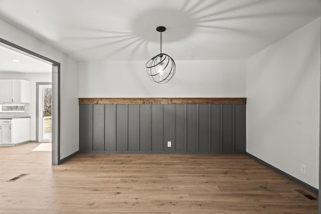 unfurnished dining area with light wood-type flooring, visible vents, and baseboards