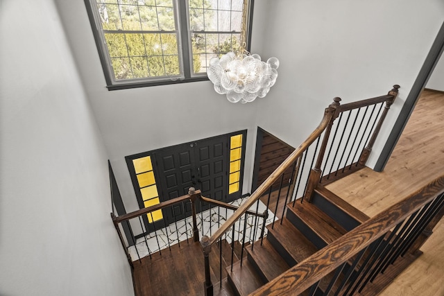 foyer featuring a towering ceiling, an inviting chandelier, wood finished floors, and stairs