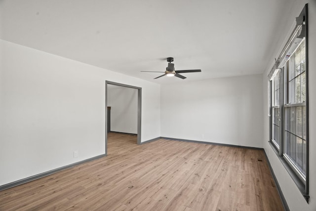 spare room with baseboards, wood finished floors, and a ceiling fan