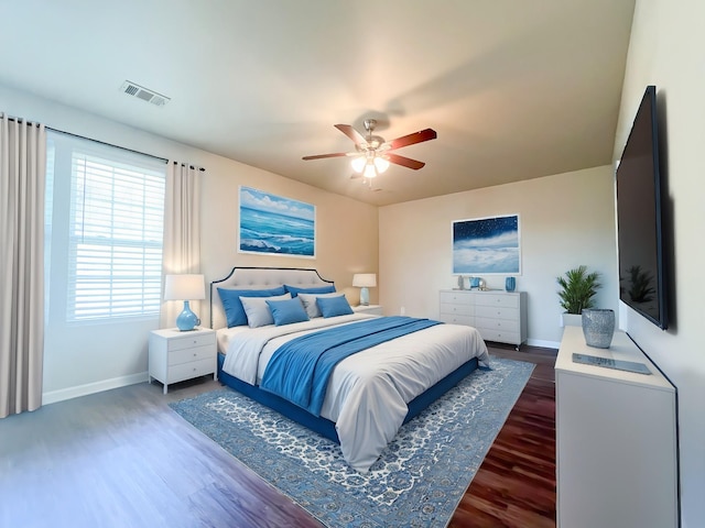 bedroom with visible vents, baseboards, wood finished floors, and a ceiling fan