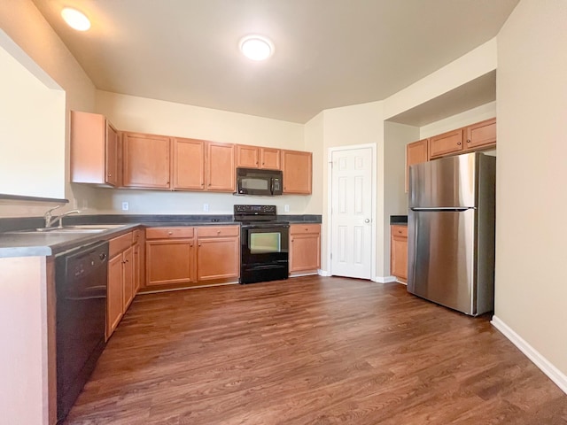 kitchen featuring black appliances, dark wood-type flooring, baseboards, and a sink