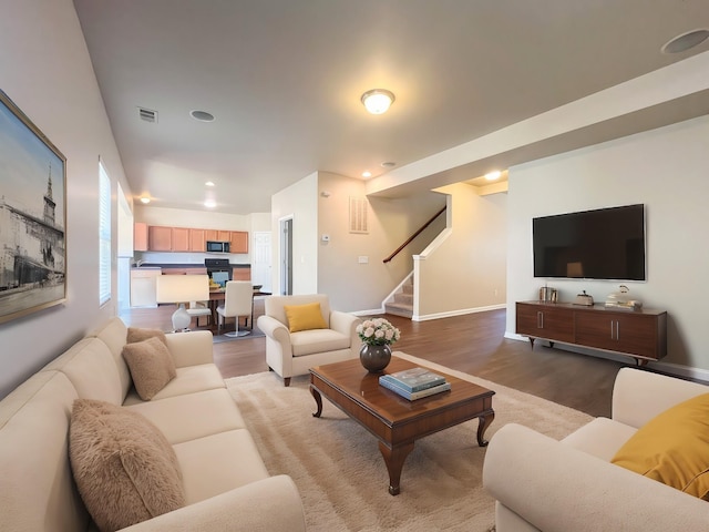 living area with stairway, wood finished floors, and visible vents