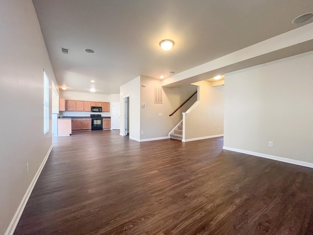 unfurnished living room featuring visible vents, baseboards, dark wood-style floors, and stairs