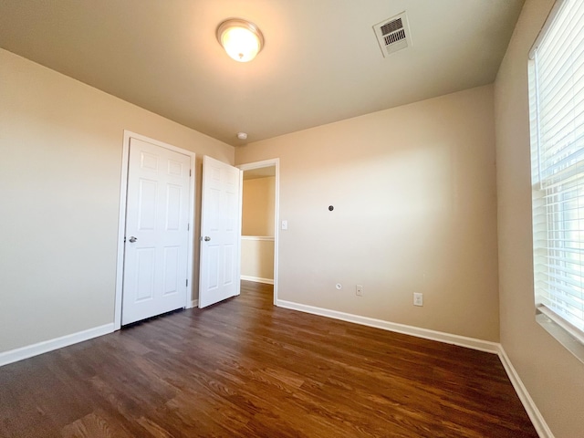 unfurnished bedroom with visible vents, baseboards, and dark wood-style floors