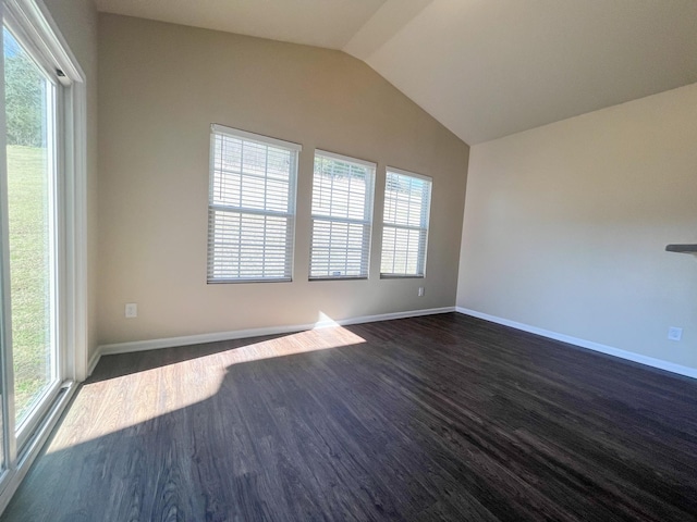 empty room with dark wood finished floors, vaulted ceiling, and baseboards