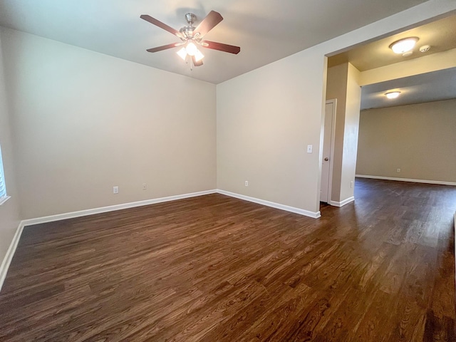 spare room featuring baseboards, dark wood-type flooring, and ceiling fan