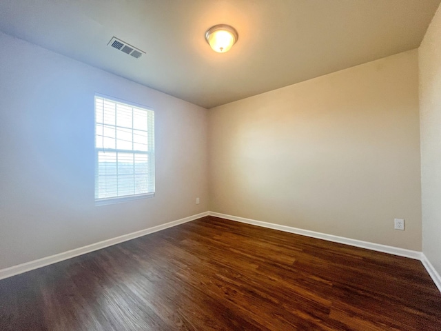 unfurnished room featuring visible vents, baseboards, and dark wood-style flooring