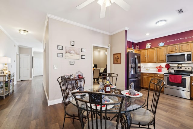 dining space with visible vents, dark wood-type flooring, ornamental molding, baseboards, and ceiling fan