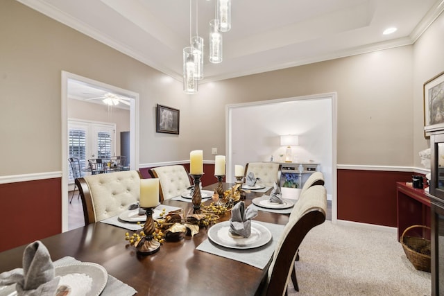 dining space with carpet flooring, a ceiling fan, crown molding, and a tray ceiling