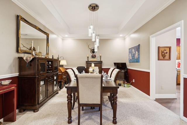 dining area featuring a tray ceiling, light carpet, baseboards, and crown molding