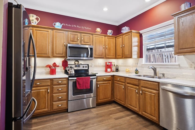 kitchen featuring decorative backsplash, brown cabinets, wood finished floors, stainless steel appliances, and a sink