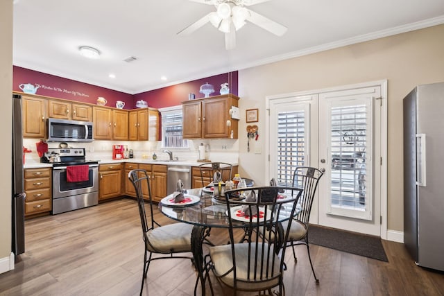 dining space featuring baseboards, visible vents, light wood finished floors, ornamental molding, and french doors