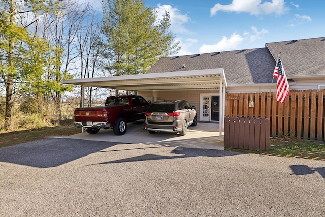 exterior space with a carport, fence, driveway, and a shingled roof