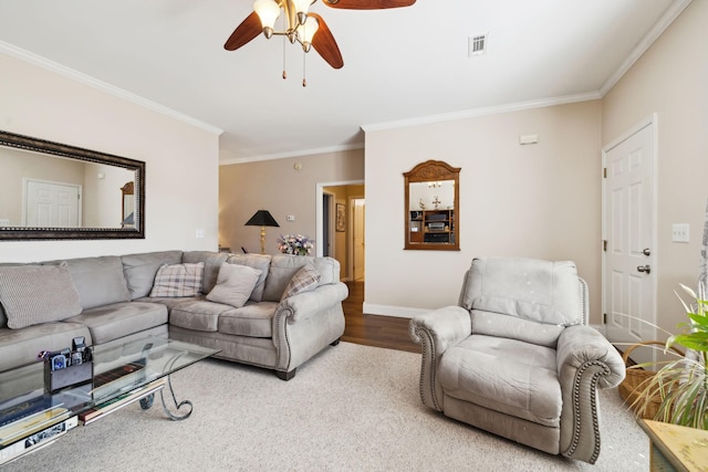 living area with baseboards, wood finished floors, visible vents, and ornamental molding