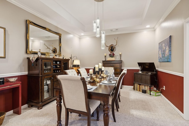 dining space with a tray ceiling, light carpet, and wainscoting