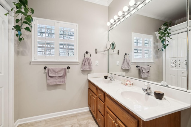 bathroom with a sink, baseboards, ornamental molding, and double vanity