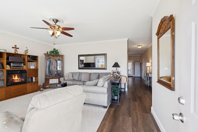 living room with a glass covered fireplace, baseboards, and ornamental molding