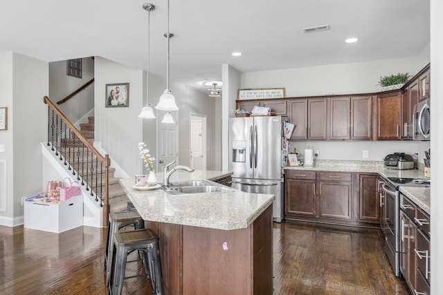 kitchen featuring visible vents, dark wood-type flooring, decorative light fixtures, stainless steel appliances, and a sink