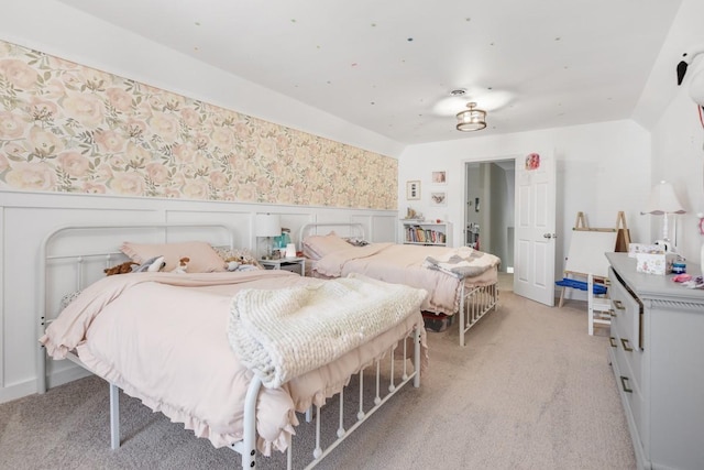 bedroom with a wainscoted wall, light colored carpet, and wallpapered walls