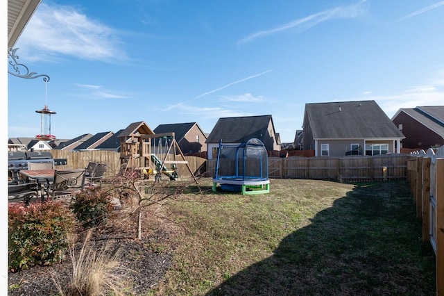 view of yard with a playground, a trampoline, a fenced backyard, and a residential view