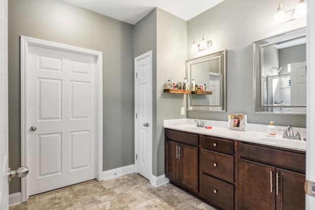 bathroom with double vanity, baseboards, and a sink