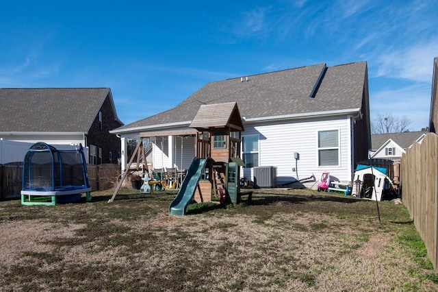 back of property featuring a playground, a trampoline, fence, and a lawn