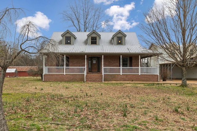 view of front of house featuring brick siding, covered porch, and metal roof