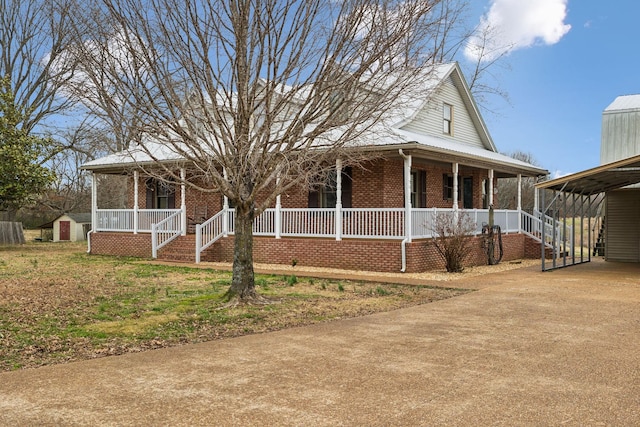 country-style home with concrete driveway, brick siding, covered porch, and a carport