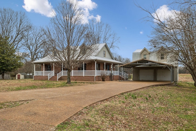 farmhouse inspired home featuring an outbuilding, covered porch, concrete driveway, a garage, and brick siding