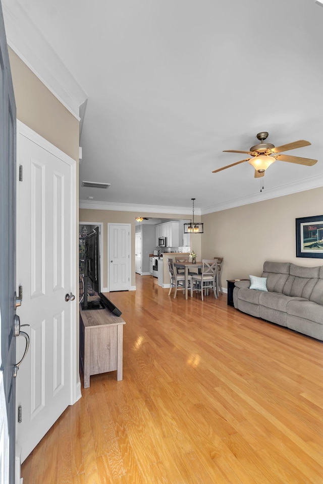 living room featuring ceiling fan, visible vents, light wood-style flooring, and ornamental molding