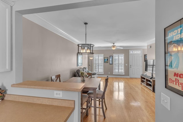 dining area featuring light wood-style flooring, crown molding, baseboards, and ceiling fan